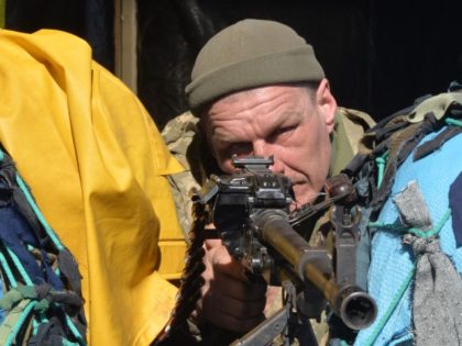 A Ukrainian serviceman aims his weapon as he stands guard at a military checkpoint in Khar