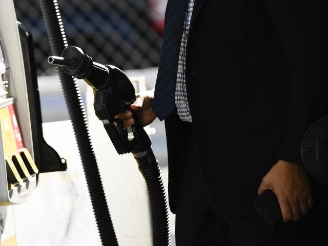 A customer returns a nozzle to a pump after fueling gasoline into a sport utility vehicle