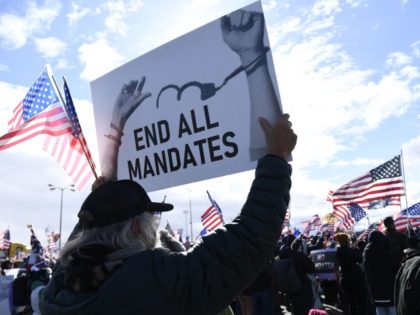 A demonstrator holds a sign reading "End All Mandates" as people gather for a rally with truckers at the start of "The Peoples Convoy" protest against Covid-19 vaccine and mask mandates in Adelanto, California, on February 23, 2022. - The convoy is headed for Washington, DC, and is expected to …