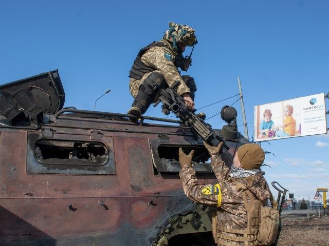 Ukrainian soldiers inspect a damaged military vehicle after fighting in Kharkiv, Ukraine, Sunday, Feb. 27, 2022. The city authorities said that Ukrainian forces engaged in fighting with Russian troops that entered the country's second-largest city on Sunday.