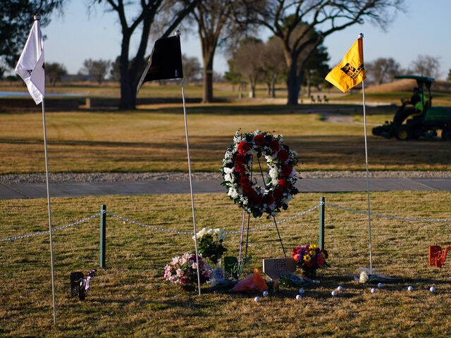 Workers prepare the course for the day near a makeshift memorial at the Rockwind Community