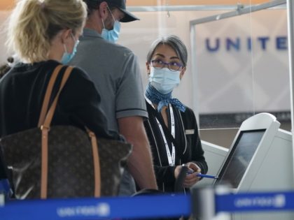 Travellers check in at a United Airlines kiosk with help from a United employee in the mai