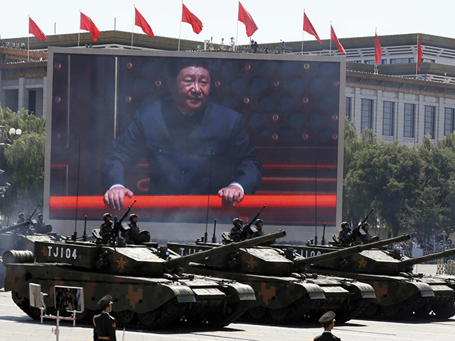 Chinese President Xi Jinping is displayed on a screen as Type 99A2 Chinese battle tanks ta