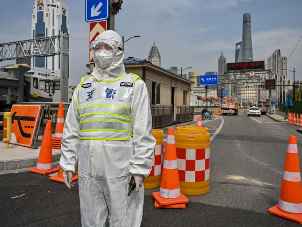 A transit officer, wearing a protective gear, controls access to a tunnel in the direction of Pudong district in lockdown as a measure against the Covid-19 coronavirus, in Shanghai on March 28, 2022. - Millions of people in China's financial hub were confined to their homes on March 28 as the eastern half of Shanghai went into lockdown to curb the nation's biggest Covid outbreak. (Photo by Hector RETAMAL / AFP) (Photo by HECTOR RETAMAL/AFP via Getty Images)