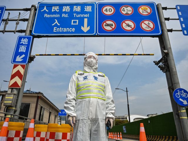 TOPSHOT - A transit officer, wearing a protective gear, controls access to a tunnel in the direction of Pudong district in lockdown as a measure against the Covid-19 coronavirus, in Shanghai on March 28, 2022. - Millions of people in China's financial hub were confined to their homes on March …
