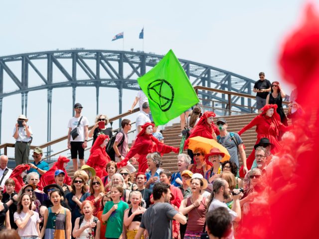 The Red Rebels, part of the Extinction Rebellion Australia demonstrator group, and other protesters participate in a climate protest rally in Sydney on December 15, 2019. - Protesters on December 15 rallied in front of the landmark Sydney Opera House demanding urgent climate action from Australia's government, as bushfire smoke …