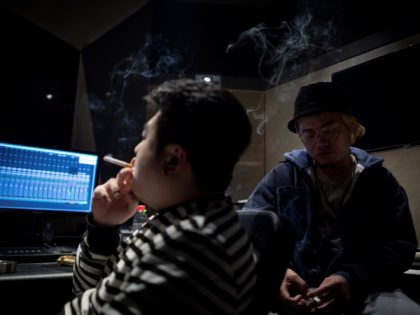 This picture taken on February 5, 2018 shows Shanghai rappers Naggy (R) and Mr Trouble, Hong Tianlin (L), smoking in their studio in Shanghai. Chinese rap and hip hop seemed poised to break out after a wildly popular singing show, but an abrupt backlash has tamed the swagger of artists …
