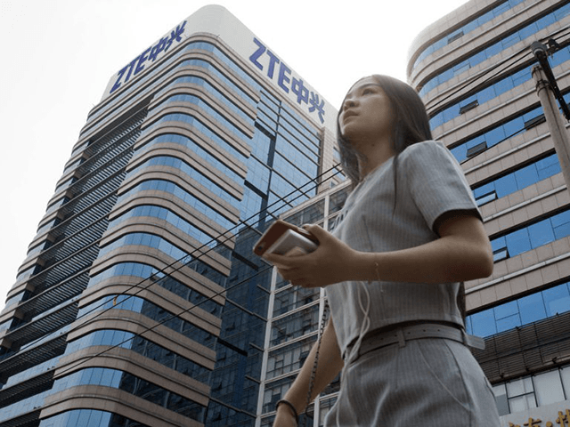 In this May 8, 2018, file photo, a woman passes by a ZTE building in Beijing, China. Chine