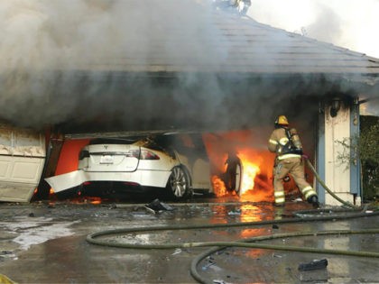 This undated photo provided by National Transportation Safety Board, The Orange County Fire Authority battles a fire on a burning vehicle inside a garage in Orange County, Calif. When firefighters removed the SUV from the garage to assess the fire , they identified the fuel source as the SUV’s high-voltage …