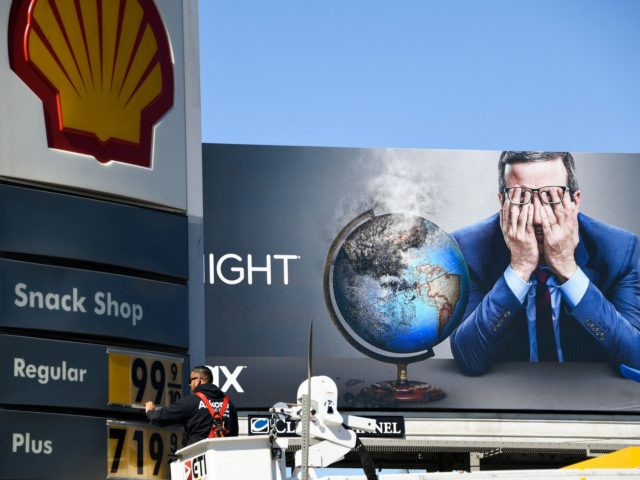 An electrical contractor repairs a sign with gasoline fuel prices above six and seven dollars a gallon at the Shell gas station at Fairfax and Olympic Blvd, near a billboard of John Oliver, in Los Angeles, California, on March 8, 2022. (Photo by Patrick T. FALLON / AFP) (Photo by …