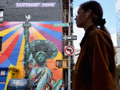 A woman walks past a mural painted by Brazilian street artist Eduardo Kobra is seen on October 29, 2018 in New York City. - The Statue of Liberty, an icon of freedom and the United States, was a welcoming sight to immigrants arriving from abroad. (Photo by Angela Weiss / …