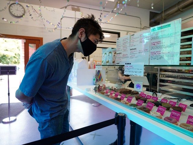 A man looks over a display case filled with mochi donuts and muffins at the Third Culture