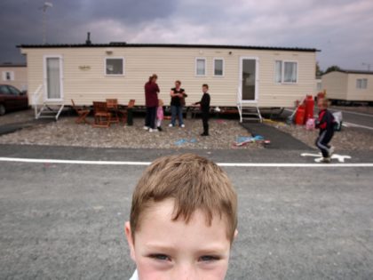 DONCASTER, UNITED KINGDOM - OCTOBER 10: (EDITORS NOTE: A GRADUATED GREY FILTER WAS USED IN THE CREATION OF THIS IMAGE) A young boy plays up to the camera near the mobile caravans for the temporary accommodation of flood victims parked in a compound on October 10, 2007, in the Village …