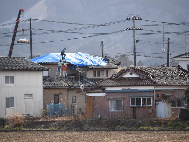 People fix damaged roofs in a neighbourhood of Soma, Fukushima Prefecture on March 17, 2022, after a 7.3-magnitude quake jolted eastern Japan the night before. (Photo by CHARLY TRIBALLEAU / AFP) (Photo by CHARLY TRIBALLEAU/AFP via Getty Images)
