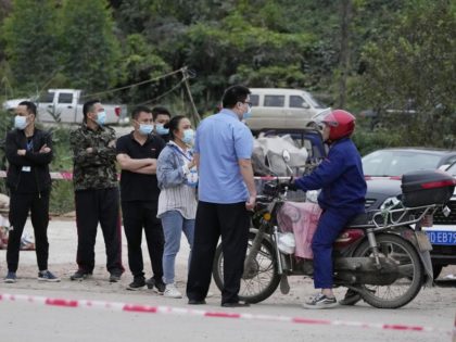 Government workers control access at the entrance to Lv village which leads to the site of the China Eastern plane crash, Tuesday, March 22, 2022, in southwestern China's Guangxi province. The crash of a China Eastern Boeing 737-800 passenger jet in China's southwest started a fire big enough to be …