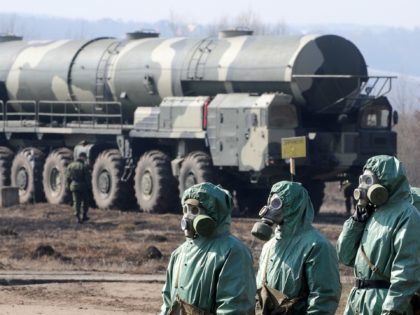 Russian soldiers wear chemical protection suits as they stand next to a military fueler on the base of a prime mover of Russian Topol intercontinental ballistic missile during a training session at the Serpukhov's military missile forces research institute some 100km outside Moscow on April 6, 2010. The US-Russia nuclear …