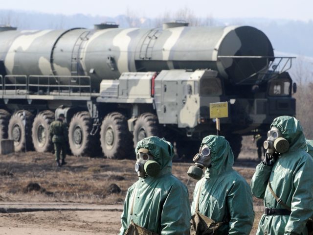 Russian soldiers wear chemical protection suits as they stand next to a military fueler on