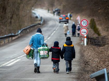 A woman with two children and carrying bags walk on a street to leave Ukraine after crossing the Slovak-Ukrainian border in Ubla, eastern Slovakia, close to the Ukrainian city of Welykyj Beresnyj, on February 25, 2022, following Russia's invasion of the Ukraine. - Ukrainian citizens have started to flee the …