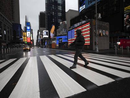 A man crosses the street in a nearly empty Times Square, which is usually very crowded on a weekday morning in New York on March 23, 2020. (AP Photo/Mark Lennihan, File)