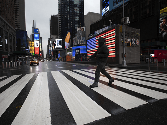 A man crosses the street in a nearly empty Times Square, which is usually very crowded on