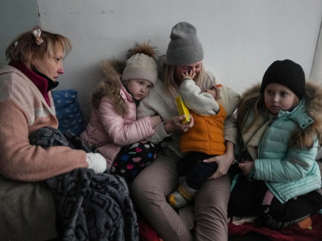 Women and children sit on the floor of a corridor in a hospital in Mariupol, eastern Ukraine Friday, March 11, 2022. Mariupol has been under siege for over a week, with no electricity, gas or water. Repeated efforts to evacuate people from the city of 430,000 have fallen apart as humanitarian convoys come under shelling. (AP Photo/Evgeniy Maloletka)