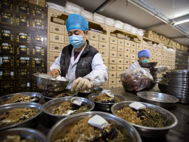 In this March 13, 2020 photo, workers fill orders for prescriptions at the Bo Ai Tang traditional Chinese medicine clinic in Beijing. With no approved drugs for the new coronavirus, some people are turning to alternative medicines, often with governments promoting them. (AP Photo/Mark Schiefelbein)
