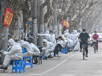 Workers in protective clothing sit near a locked down area after the detection of new cases of Covid-19 in Shanghai on March 14.