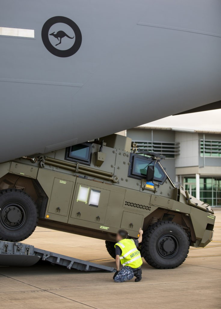 A Royal Australian Air Force air movements operator from No. 23 Squadron guides a Bushmaster protected mobility vehicle bound for Ukraine onto a C-17A Globemaster III aircraft at RAAF Base Amberley, Queensland.