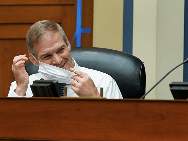 Rep. Jim Jordan, R-Ohio, smiles while adjusting his protective mask during a House Select