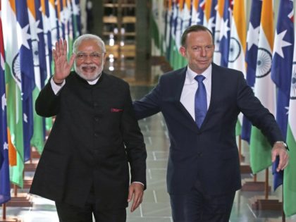 FILE - In this Nov. 18, 2014, file photo, India's Prime Minister Narendra Modi, left, waves as he is escorted by Australian Prime Minister Tony Abbott as they leave the House of Representatives at Parliament House in Canberra, Australia. An India-Australia free trade agreement would signal the "democratic world's tilt …