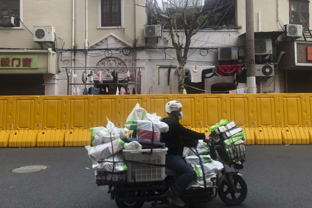 FILE - A delivery man passes by barriers set up to lock down a community in Shanghai, China, on March 30, 2022. Residents of Shanghai are struggling to get meat, rice and other food supplies under anti-coronavirus controls that confine most of its 25 million people in their homes, fueling frustration as the government tries to contain a spreading outbreak.(AP Photo/Chen Si, File)