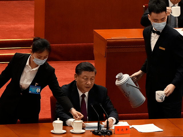 A hostess serves a drink as Chinese President Xi Jinping speaks during the commendation ce