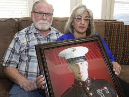 FILE - Joey and Paula Reed pose for a photo with a portrait of their son Marine veteran an
