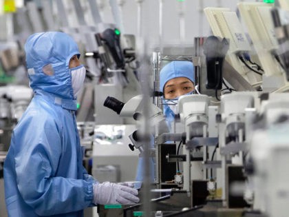 FILE - Employees wearing protective equipment work at a semiconductor production facility for Renesas Electronics during a government organized tour for journalists in Beijing, on May 14, 2020. House Democrats are poised to approve legislation Friday, Feb. 4, 2022, that they say positions the United States to better compete with …