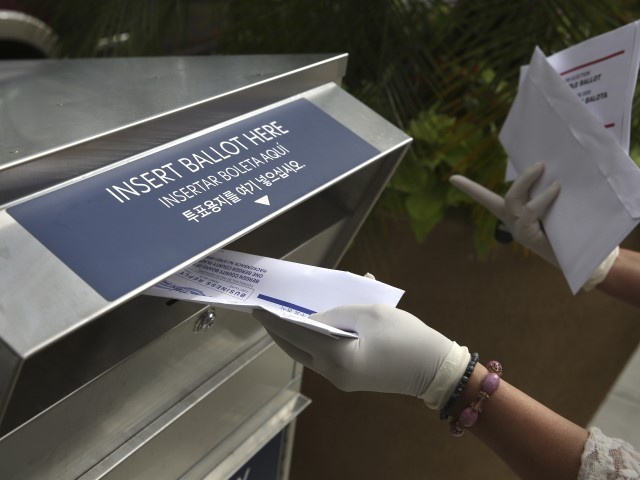 FILE - In this July 7, 2020, file photo a woman wearing gloves drops off a mail-in ballot at a drop box in Hackensack, N.J. With the Trump administration openly trying to undermine mail-in voting this fall, some election officials around the country are hoping to bypass the Postal Service by installing lots of ballot drop boxes in libraries, community centers and other public places. (AP Photo/Seth Wenig, File)