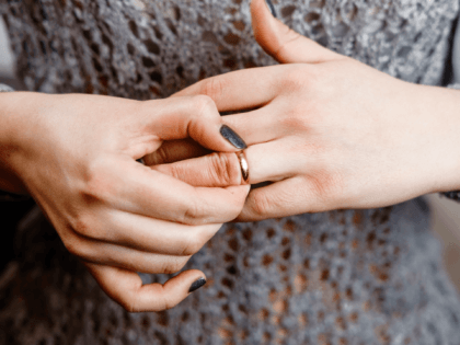 woman takes off an engagement ring, family conflict, close-up - stock photo