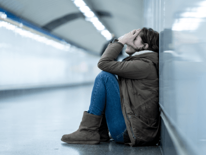 Young adult felling shame depressed and hopeless sitting alone on subway city ground in De