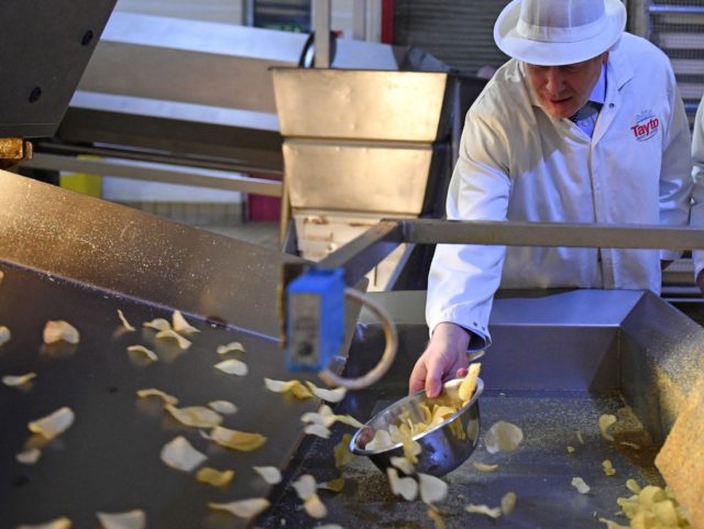 Watched by Tayto Chairman Stephen Hutchinson (R), Britain's Prime Minister Boris Johnson (L) catches crisps in a bowl during a general election campaign visit to the Tayto Castle crisp factory in County Armagh, Northern Ireland, on November 7, 2019. - Britain's two main parties promised billions of pounds of investment …