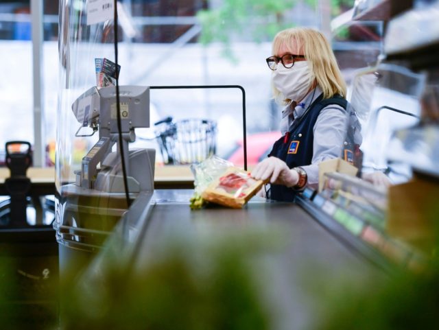 A cashier of food discounter ALDI wears a face mask as she serves a customer in Duesseldorf, western Germany, on April 29, 2020 amid the novel coronavirus COVID-19 pandemic. - From April 29, 2020 in Germany, masks are needed to enter shops, which began to open last week after the …