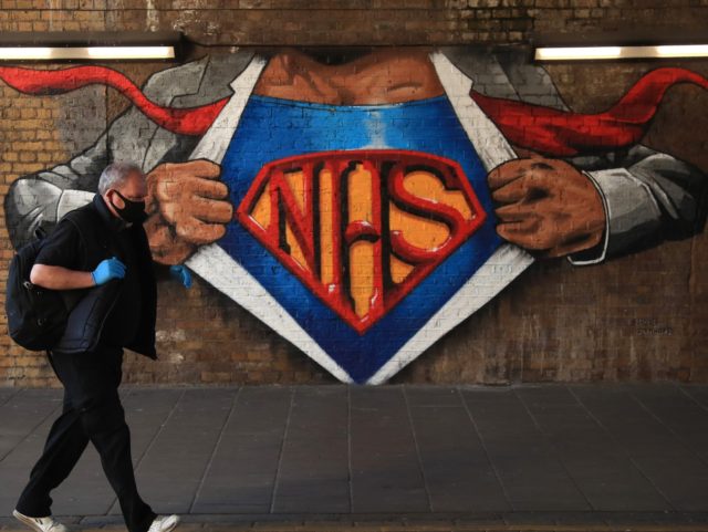 LONDON, ENGLAND - MAY 29: A man wearing a face mask and gloves walks past an NHS mural by