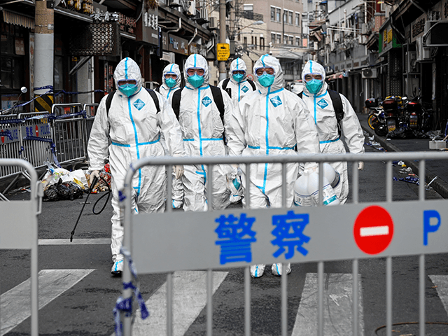 Health workers in protective gear walk out from a blocked off area after spraying disinfec