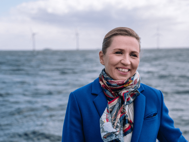 Denmark's Prime Minister Mette Frederiksen smiles as she stands on a boat with wind turbines of the Middelgrunden offshore wind farm in the background, in Oeresund between Denmark and Sweden, outside Copenhagen, on April 22, 2021. - During this trip HOFOR (Greater Copenhagen Utility), who's aim is to create sustainable …
