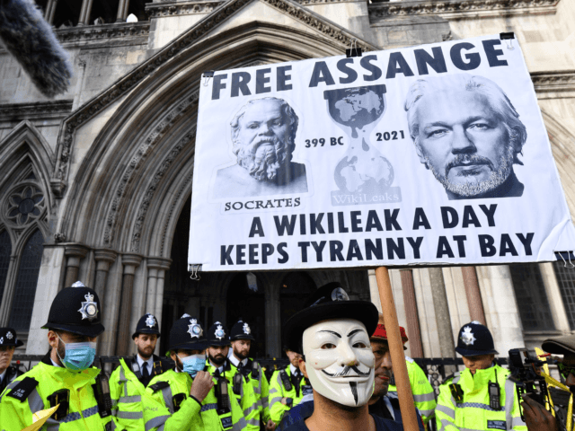 Police officials stand guard as protestors in support of Wikileaks founder Julian Assange hold placards outside the Royal Courts of Justice in London during an appeal hearing by the US government against the UK's refusal to extradite him on October 27, 2021. - The United States told a British court …