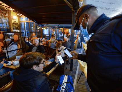 A policeman checks the Covid-19 health pass of customers in a bar in Saint-Malo, northwestern France, on November 19, 2021. - As mainland France experiences a new Covid-19 rebound, health authorities recommend a vaccine booster dose to people aged 40 and over, according to a press release on November 19, …