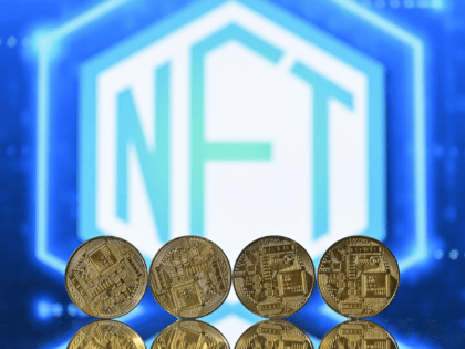 An illustration picture taken in London on December 30, 2021, shows gold plated souvenir cryptocurrency coins arranged by a screen displaying a NFT (Non-Fungible Token) logo. - Non-fungible tokens or NFTs are cryptographic assets stored on a blockchain with unique identification metadata that distinguish them from each other. (Photo by …