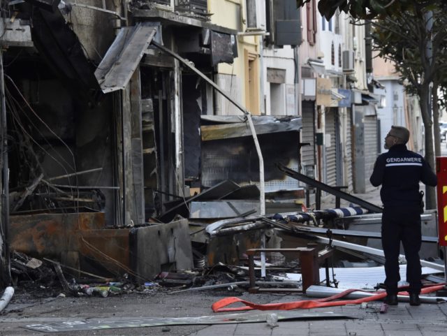 A gendarme walks by the site of a fire that broke out the day before following an explosio