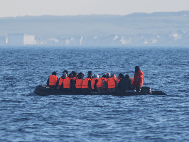 Migrants wearing life jackets sit in a dinghy as they illegally cross the English Channel