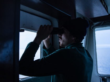 A crew member observes the flow of migrants at sea through binocular from the Abeille Languedoc, an ocean-going tug specializing in the rescue of ships in distress, and which has been docked for the past 26 years in Cherbourg, monitoring the English Channel between the Cotentin and the Pas de …