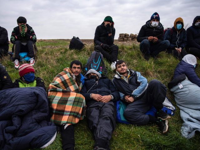 TOPSHOT - Migrants wait for a bus in Calais, north of France, on March 16, 2022, to go bac