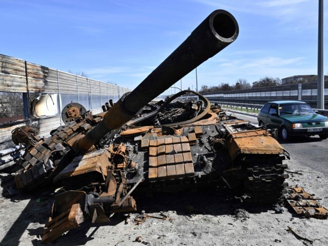 A car drives past a burnt Russian tank on a road west of Kyiv, on April 7, 2022, during Russia's military invasion launched on Ukraine. - Six weeks after Russia invaded its neighbour, its troops have withdrawn from Kyiv and Ukraine's north and are focusing on the country's southeast, where …